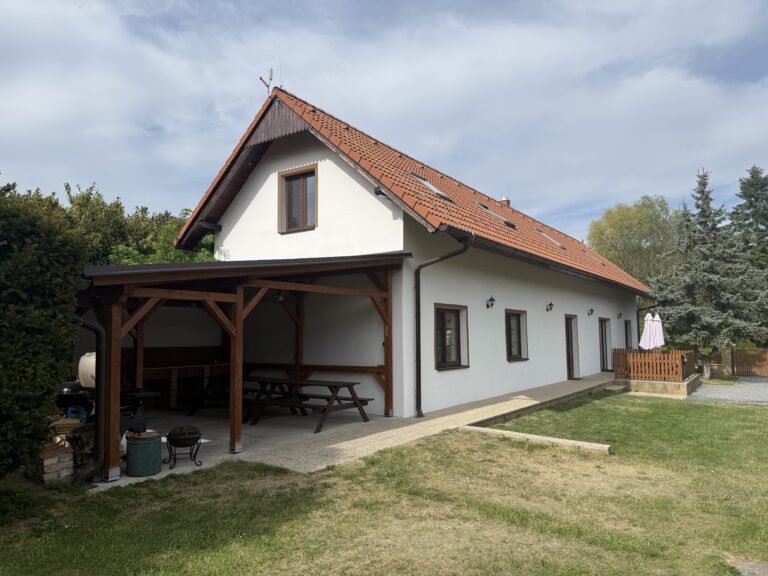 Chalupa s krytým posezením a piknikovým stolem před domem